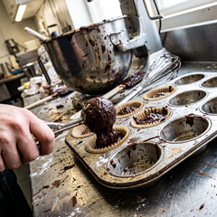Porzionatura di impasto al cacao nei pirottini di una teglia per muffin