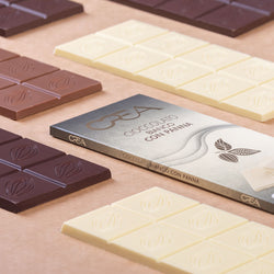 Piccole tavolette di cioccolato al latte, bianco e fondente Modecor disposte su una torta