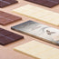 Piccole tavolette di cioccolato al latte, bianco e fondente Modecor disposte su una torta